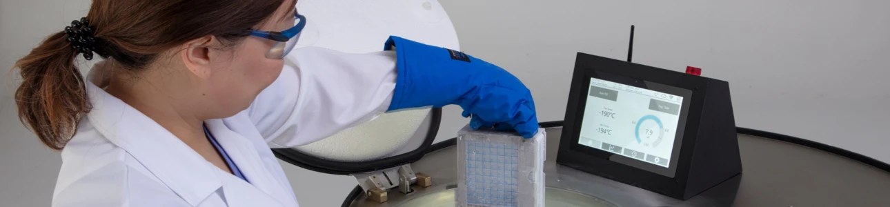 Lab staff handling labware atop a LN2 freezer tank