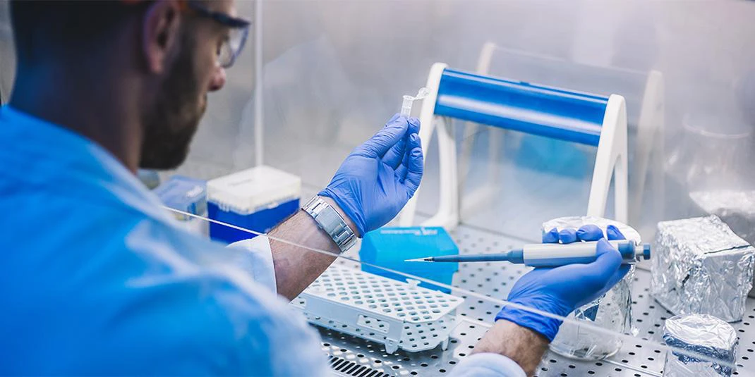 Scientist at clean bench with microcentrifuge tube and pipette